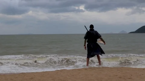 A man in black stands against the backdrop of a worrying sea and island Stock Footage 124911920