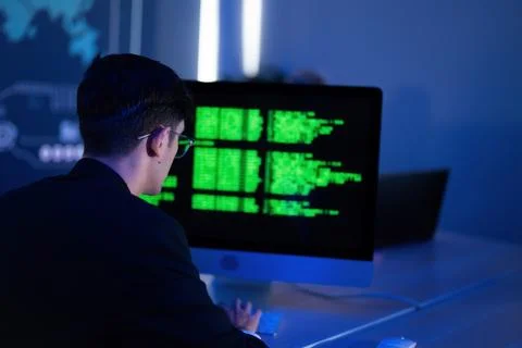 Man in black suit working on computer with green data on screen in modern o.. 스톡 사진