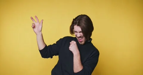 Man in black sweater dancing joyfully against yellow background. Stock Footage 315161147