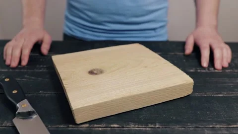 Man at black table cutting halva in two halves on chopping wooden kitchen boa Stock Footage 130813915