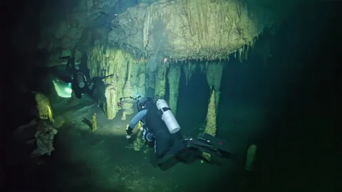 A man in a black wet suit is diving in a cave Stock Footage 299461065