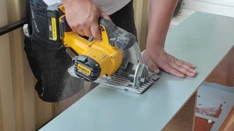 Man in black work shorts saws old chipboard furniture for recycling on balcony Stock Footage 156573522