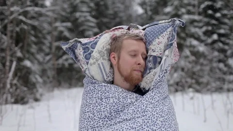 Man in a Blanket and With a Pillow Sleeping in the Winter Forest Stock Footage