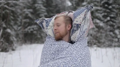 A Man in a Blanket and With a Pillow Sleeping in the Winter Forest Stock Footage