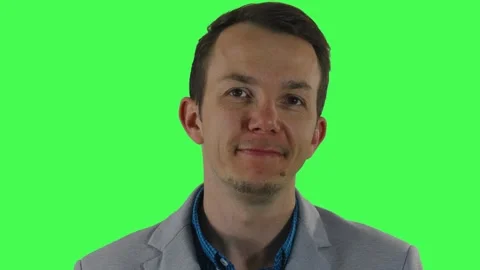 Man in blazer smiling gently and maintaining relaxed eye contact on green screen Stock Footage 309857971