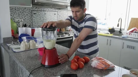 A man blending garlic in a blender in the kitchen at daytime in 4k Stock Footage 185333910