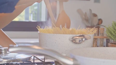 Man blending spaghetti pasta in boiling water pot.Young people couple cooking 動画素材 108108849