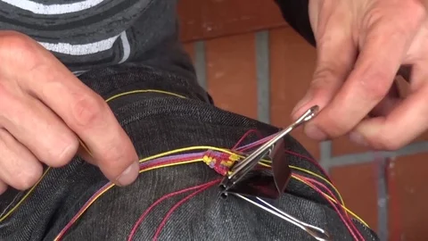 Man blends with colored thread a wrist bracelet put at the hands Stock Footage 72266543