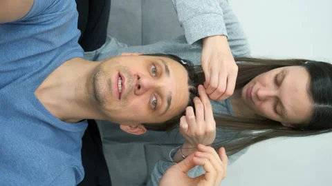 Man blogger is speaking at camera while woman is doing his hair french braids. Stock Footage 168006248