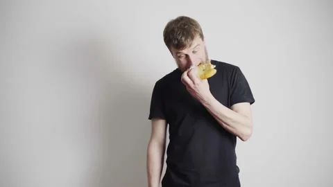 Man with a blond beard, in a black T-shirt on a white background, eats Video stock 131057553