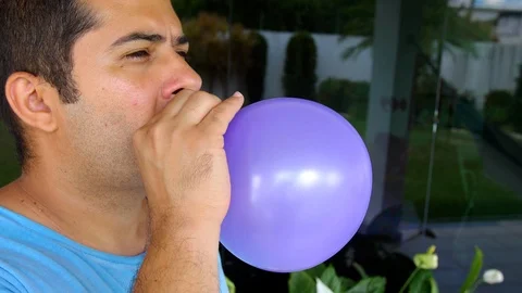 Man blowing up balloon, then it runs away from his hands and deflate Stock Footage 123664233