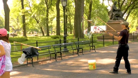 Man blowing large soap bubble with tri-strings wand in the air while Stock Footage 112983092