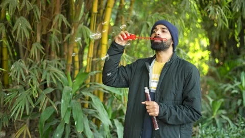 Man blowing soap bubbles in a bamboo forest Stock Footage 341763680