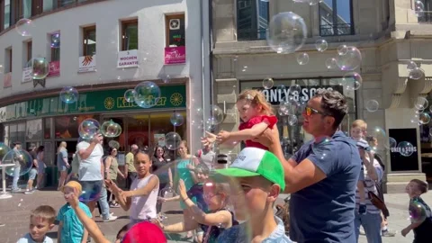 A man is blowing soap bubbles in downtown Lörrach Stock Footage 338011834