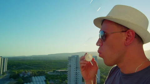 Man Blowing Soap Bubbles at Sunset Cityscape Stock-Footage 331066905