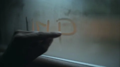 Man blows and writes help on the condensation of a window Stock Footage 145845967