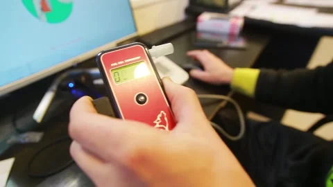 A man blows into a breathalyzer to measure the amount of alcohol in his blood 库存影片 246714323