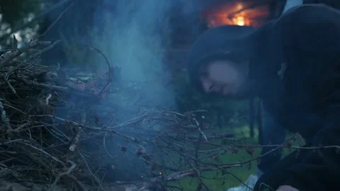 A man blows up a fire in a bonfire of branches on a country plot Stock Footage 172310835