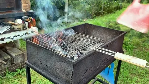 Man blows up a fire in the grill Vídeos de archivo 129755526