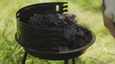 Man blows fire on grill preparing charcoal for perfect outdoor barbecue in Stock Footage 310741028