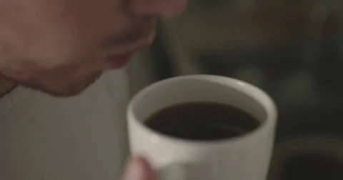 Man blows on hot cup of tea Stock Footage 78038322