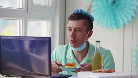A man blows out a candle on a cake and waves his hello to a laptop. Stock Footage 131022915