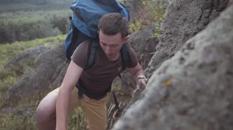 Man with blue backpack hiking and climbing the rocks, reaching the top of Ural Stock Footage 54156600