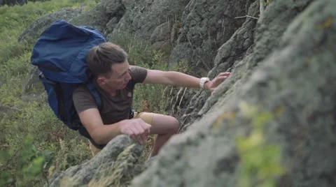 Man with blue backpack hiking and climbing the rocks, reaching the top of Ural Stock Footage 54156668
