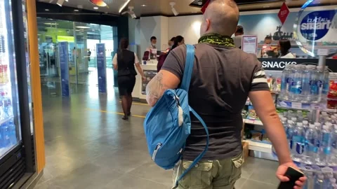 Man with a blue backpack walks down a hallway past shops Vídeos de archivo 139745297