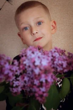 A man with blue eyes holds a bouquet of lilacs Stock Photos