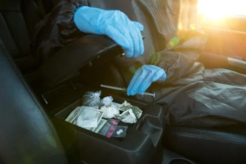 A man in blue gloves takes out a syringe with drugs from the glove compartment. Stock Photos