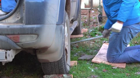 Man in a blue jacket jacks up the car in the countryside. Stock Footage 143575147