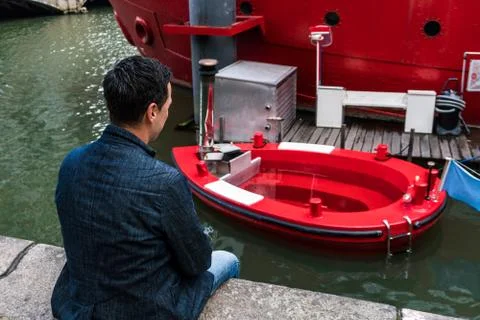 Man in blue jacket looking at Red Hot Tag with melted stove in Rotterdam. The Stock Photos