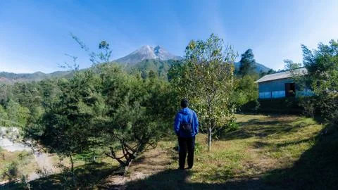 A man with blue jacket, stand in front of beautiful Merapi Mountain in Yogyak Stock Photos
