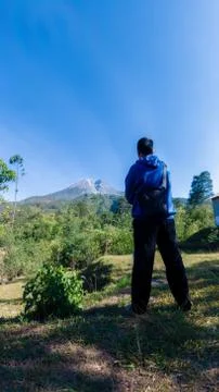 A man with blue jacket, stand in front of beautiful Merapi Mountain in Yogyak Stock Photos