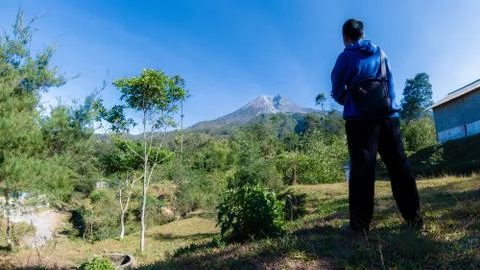 A man with blue jacket, stand in front of beautiful Merapi Mountain in Yogyak Stock Photos