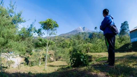 A man with blue jacket, stand in front of beautiful Merapi Mountain in Yogyak Stock Photos