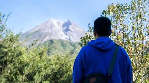 A man with blue jacket, stand in front of beautiful Merapi Mountain in Yogyak Stock Photos