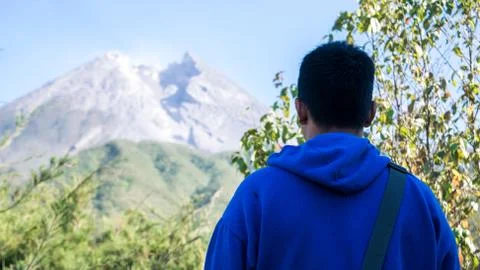 A man with blue jacket, stand in front of beautiful Merapi Mountain in Yogyak Stock Photos