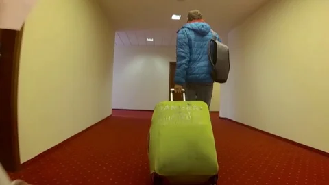 Man in a blue jacket with a suitcase is walking down the hotels corridor Video stock 109547562