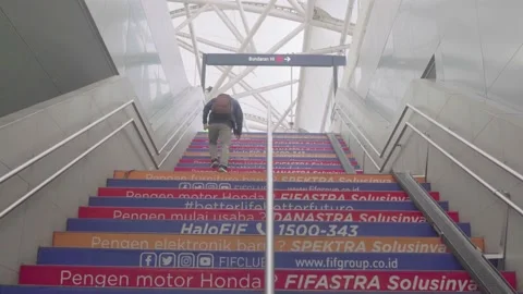 A man in a blue jacket was walking up the stairs to board the MRT Stock Footage 222033344