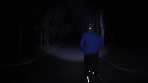 Man with blue jacket wearing headlamp training in the city park at night  Video stock 147269337