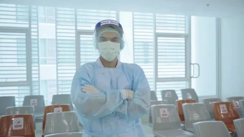 A man in a blue lab coat and a mask stands in front of a row of chairs. The chai Stock Footage 248236930