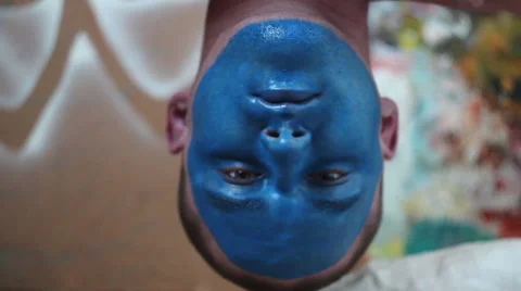 Man with blue painted face hanging upside down and falling asleep Stock Footage 48868406