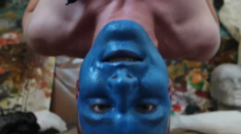 Man with blue painted face hanging upside down and smiles Stock Footage 48869600