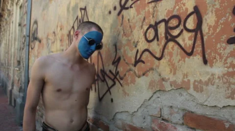 Man with blue painted face walking through ruined part of town Stock Footage 48869777