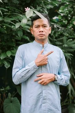 Man in blue points with greenery backdrop, captivating gaze Stock Photos