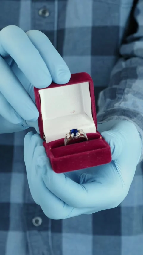Man in blue protective gloves holding red box with wedding ring. Vertical video Stock Footage 296497350