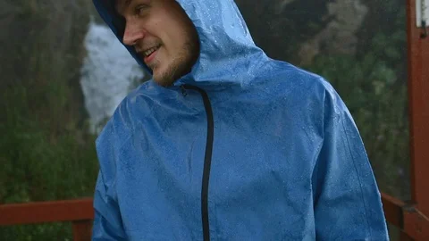 Man in blue raincoat under the rain and splash of water dancing and have fun Stock Footage 87997226