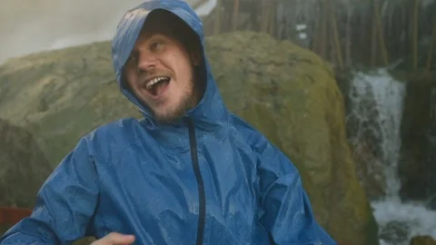 Man in blue raincoat under the rain and splash of water dancing and have fun Stock-Footage 87999940